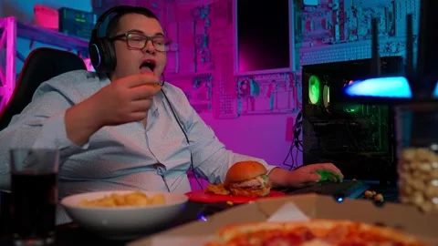 The Fat gamer plays at the computer and eats a burger and pizza. A Thick program Stock-Footage 220420640