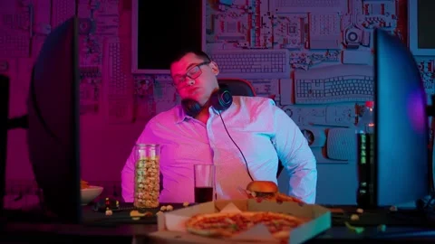 The Fat gamer plays at the computer and eats a burger and pizza. A Thick program Stock Footage 220422050