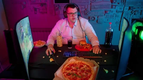 The Fat gamer plays at the computer and eats a burger and pizza. A Thick program Stock Footage 220423669
