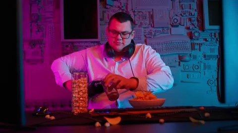 The Fat gamer plays at the computer and eats a burger and pizza. A Thick program Stock Footage 220423801