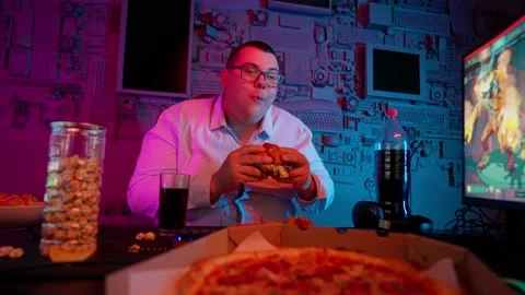The Fat gamer plays at the computer and eats a burger and pizza. A Thick program Stock Footage 220423985