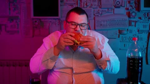 The Fat gamer plays at the computer and eats a burger and pizza. A Thick program Stock-Footage 220423990