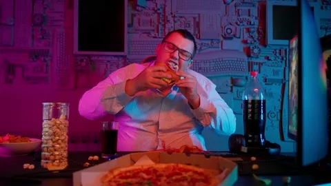 The Fat gamer plays at the computer and eats a burger and pizza. A Thick program Stock-Footage 220424008