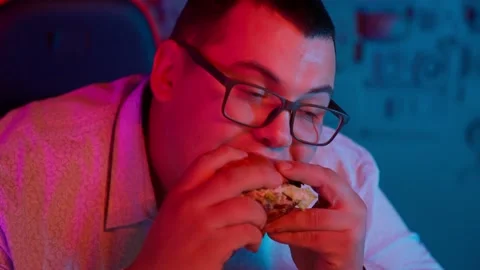 The Fat gamer plays at the computer and eats a burger and pizza. A Thick program Stock-Footage 220424059
