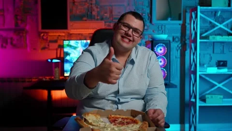 The Fat gamer plays at the computer and eats a burger and pizza. A Thick program Stock Footage 220545764