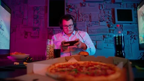 The Fat gamer plays at the computer and eats a burger and pizza. A Thick program Stock-Footage 220545805