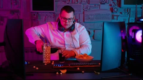The Fat gamer plays at the computer and eats a burger and pizza. A Thick program Stock Footage 220545916