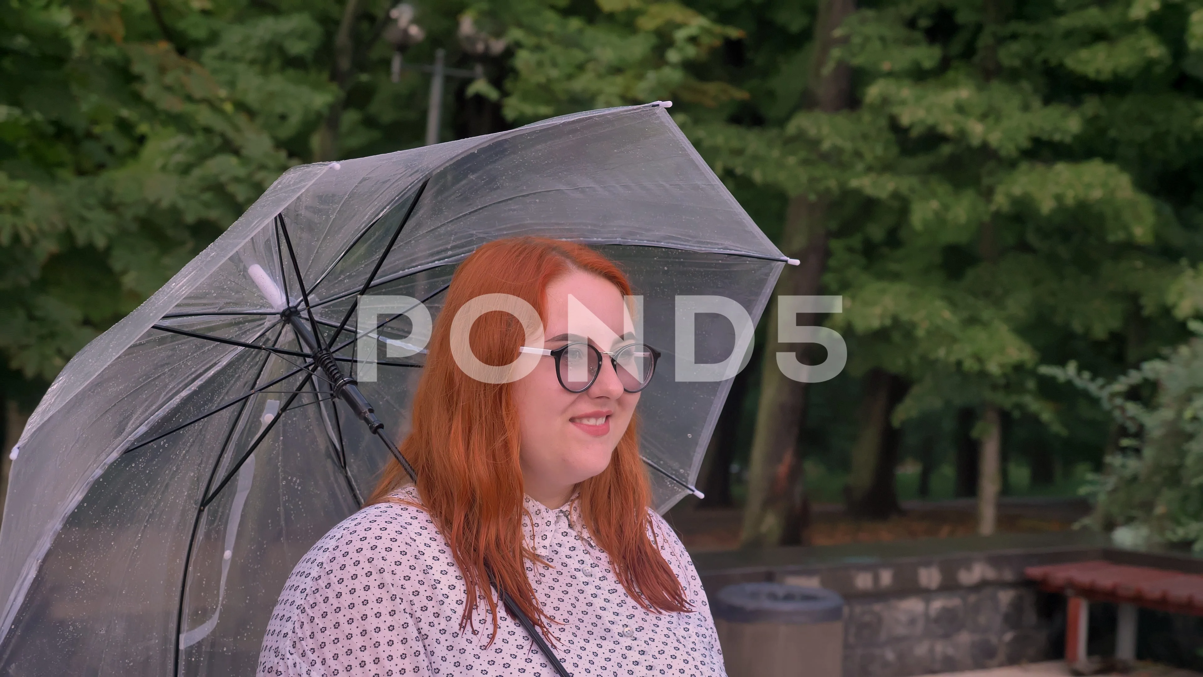 Fat ginger girl with glasses is crossing on road in park in rainy weather,  going