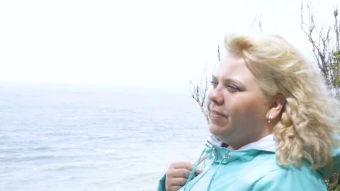 Fat Girl with beautiful hair standing in wind against sea landscape and look Stock Footage