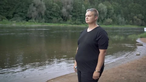 Fat guy drinks water after training in the park Stock Footage 132150932
