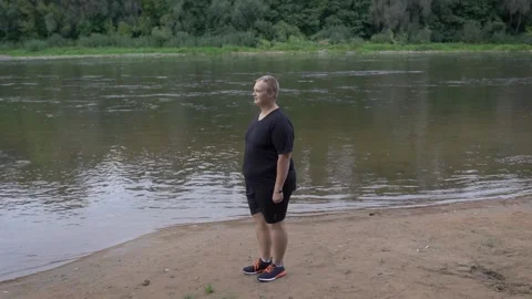 Fat guy jumping on the background of the river. Stock Footage 132827912