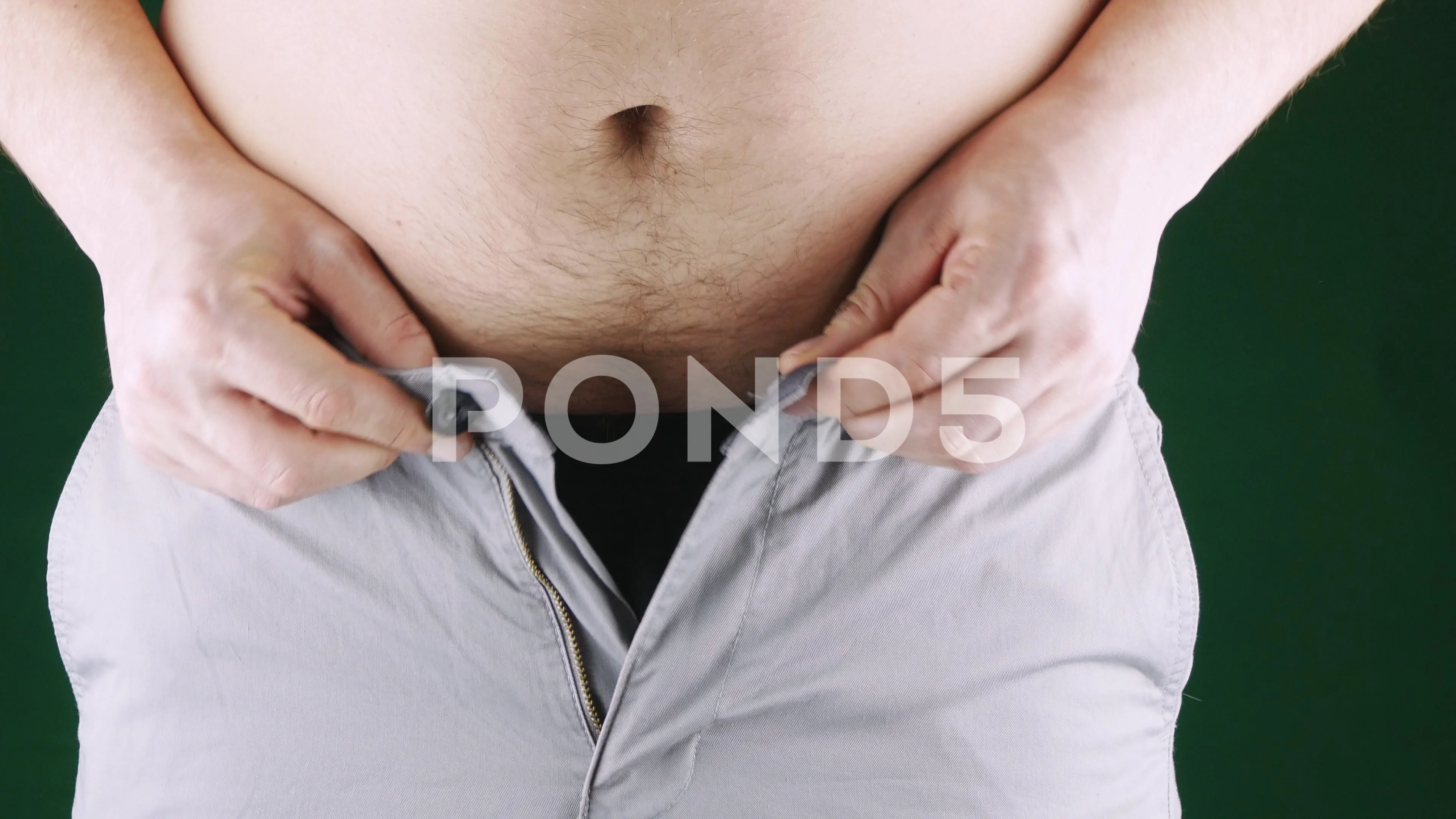 Fat man trying to put on pants. Big Paunch Stock Photo by