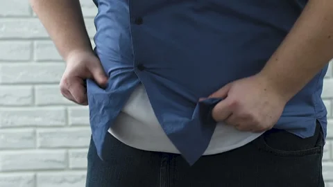 Fat man with difficulty buttoning shirt on huge belly, plus-size insecurities Stockbeeldmateriaal 89489793