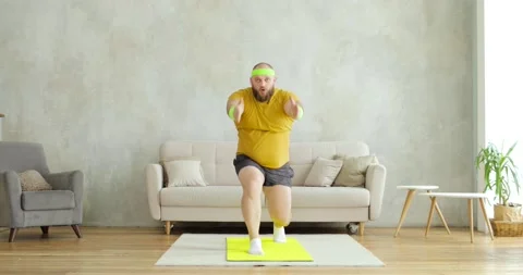 Fat man doing squats in lunges exercise with hands up standing on mat at home. Stock-Footage 149033073