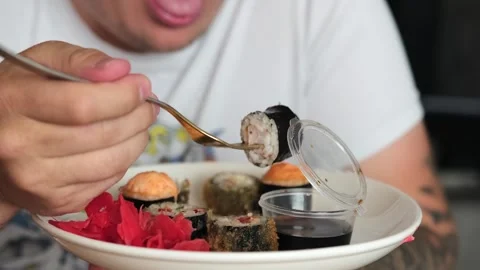 Fat man dunks in soy sauce and wasabi Japanese rolls. Stock Footage 246520140