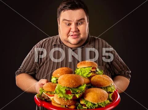 Fat man eating fast food hamberger. Breakfast for overweight person. Stock Photos