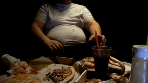 Fat man eats junk food and drinks soda, watches TV at home. Gluttony and Stock Footage 129963017