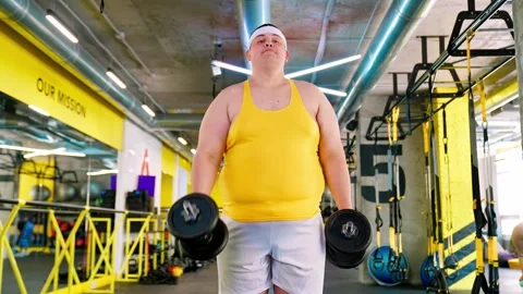 The fat man is exercising in the gym and looking at the burger and pizza. Obesit Stock Footage 244237792