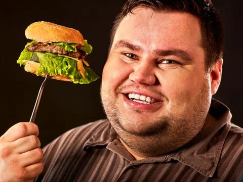 Fat man face eats burger on fork Stock Photos