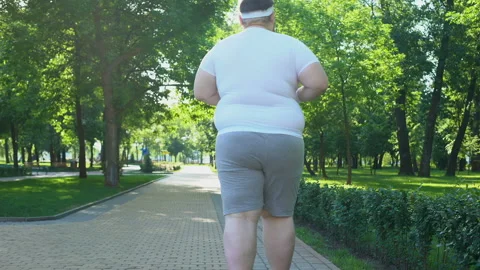 Fat man jogging in park, beginning of weight loss program, healthy lifestyle Stock Footage 91662350