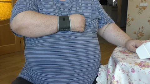 Fat man measures his own blood pressure Stock Footage 174097464