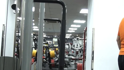 Fat man picks up small dumbbells looking in a mirror in a gym Stock Footage 96728069