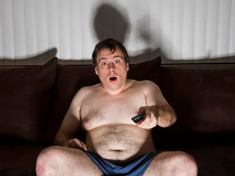 Fat man shocked while watching TV Stock Photos