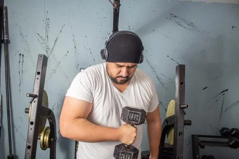 Fat man training lifting weights in home gym making effort face. fitness conc Photos