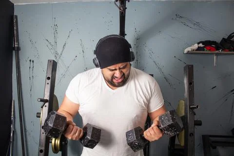 Fat man training lifting weights in home gym making effort face. fitness conc Fotos Stock