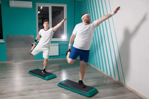 Fat man is very hardworking doing exercises on steps with his hands up during Stock Photos