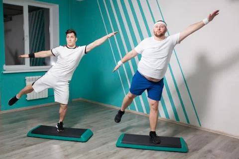 Fat man is very hardworking doing exercises on steps with his hands up during Stock Photos