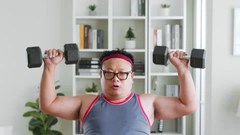 Fat middle-aged asian man in sportswear workout with dumbbell at home Stock Footage 231544862