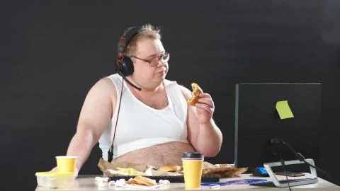 Fat programmer works at home remotely at a computer, a person works and eats at 写真素材
