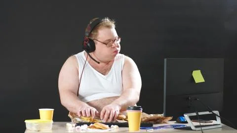 Fat programmer works at home remotely at a computer, a person works and eats at Foto stock