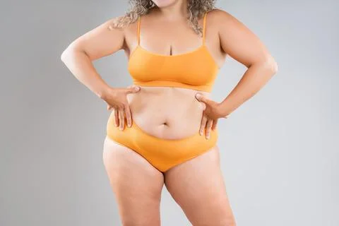 Fat woman in orange underwear on gray studio background, obesity and cellulit Stock Photos