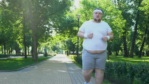 Fat young man jogging in park, obesity concept, struggling with insecurity Stock Footage 91662477