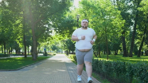 Fat young man jogging in park, obesity concept, struggling with insecurity Stock Footage 91670581