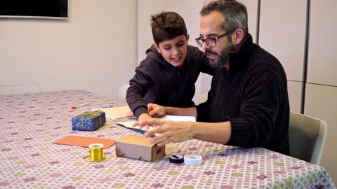 Father and 8 year old son wrapping Christmas gifts Stock Footage 345253404