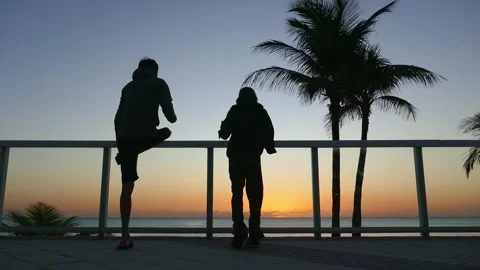 Father and child doing exercises on the ocean shore at sunrise Stock Footage 269719816