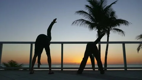 Father and child doing exercises on the ocean shore at sunrise Stock Footage 269719818