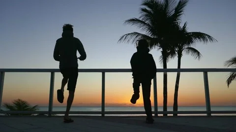 Father and child doing exercises on the ocean shore at sunrise Stock Footage 269719823