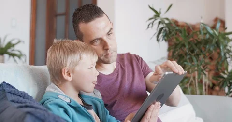 Father and child looking using tablet device at home Stock Footage 120345112