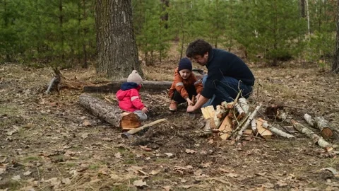 Father and children digging the ground in the forest to prepare a future camp 库存影片 334601025
