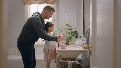 Father and daughter having fun dad helping little girl get ready  in bathroom Stock Footage