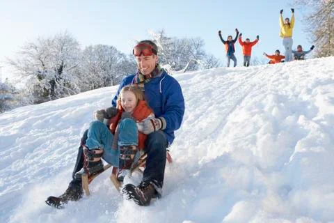 Father and daughter having fun sledging down hill Stock Photos