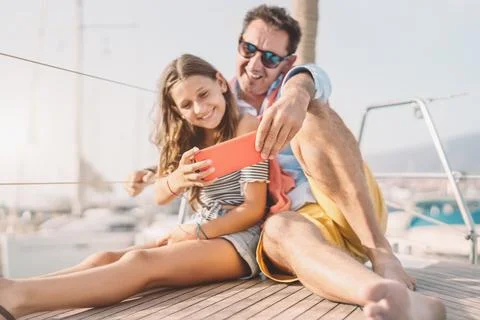 Father and daughter taking selfie smartphone camera during sailboat trip Stock Photos
