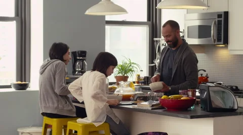 Father and daughters interacting while having breakfast in kitchen Stock Footage 63860983