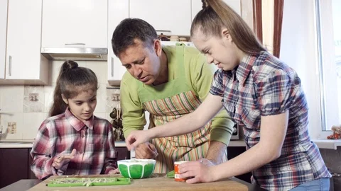 Father and daughters in the kitchen preparing green salad Stock Footage 110875547