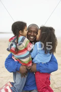 Father and daughters relaxing on winter beach break Stock Photos