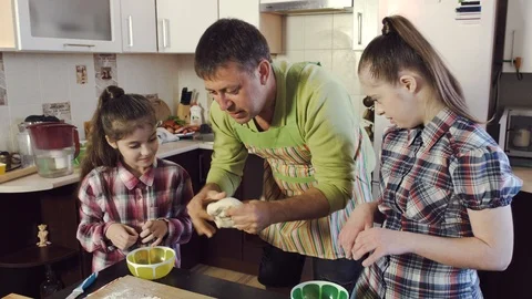Father and daughters stretch thick dough into long strip 스톡 동영상 107975635